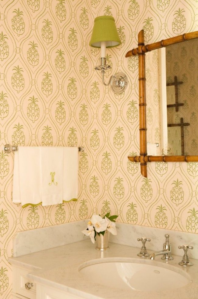 Salle de bain éclectique avec imprimé vert ananas et cadre de miroir en bambou accentuant les thèmes tropicaux
