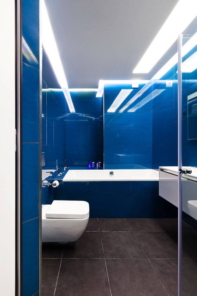Une solution audacieuse et très colorée : le bleu brillant du carrelage et l'éclairage froid dans une petite salle de bain combinée