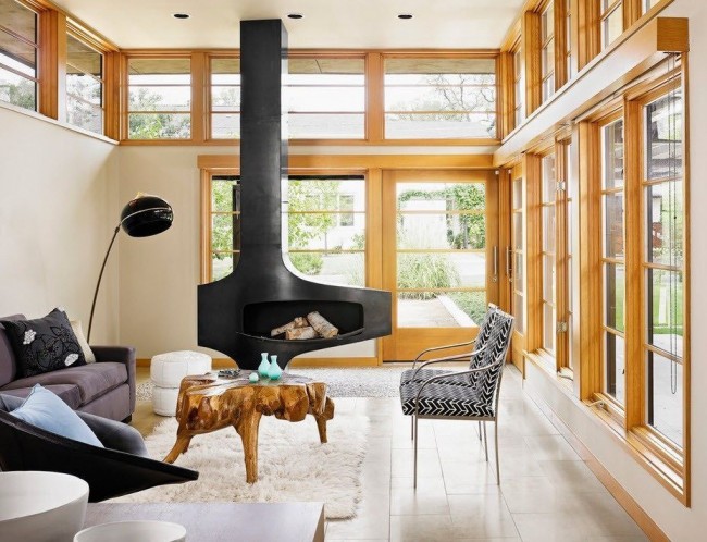 Des fenêtres en bois marron clair et une table basse en bois inhabituelle sont idéalement combinées avec une cheminée noire massive stylisée