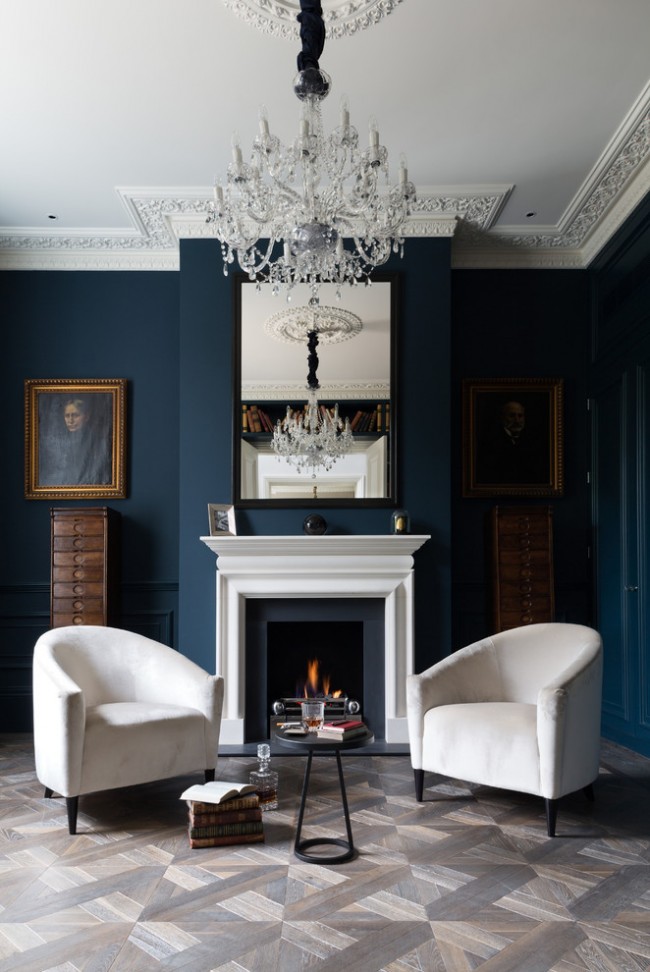 Le stuc au plafond et le lustre en cristal pompeux sont équilibrés par la stricte couleur bleu foncé des murs et la simplicité du mobilier.  Portez une attention particulière au motif et à la couleur du parquet
