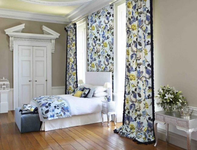 Style anlian dans la conception de la chambre avec des rideaux colorés, qui sont soutenus par un insert de papier peint avec le même motif et le même couvre-lit