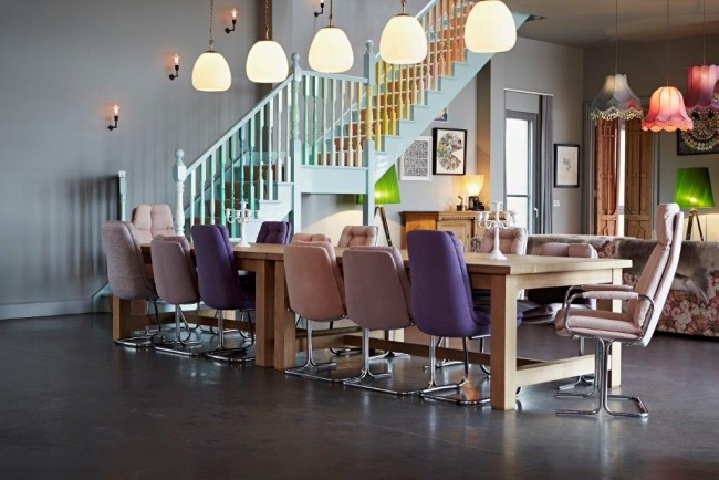 L'ambiance ludique du salon est créée par sa palette de couleurs, en particulier les chaises violettes dans différentes nuances.