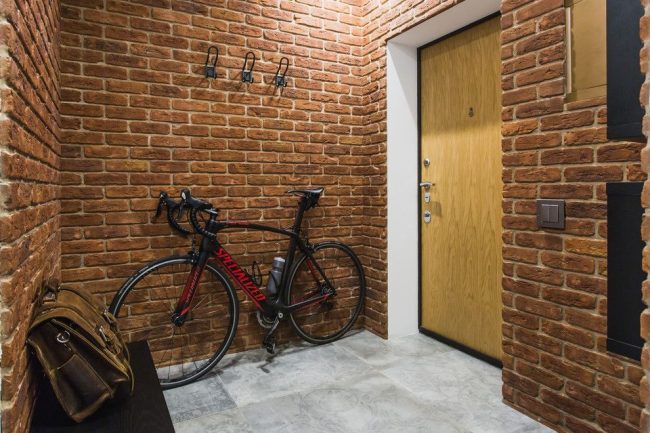 Couloir de style loft avec murs en briques et porte d'entrée marron clair