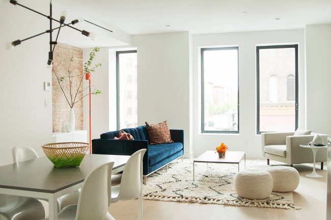 Le canapé turquoise foncé a l'air aussi luxueux et accentué que possible dans l'intérieur clair du salon dans le style scandinave