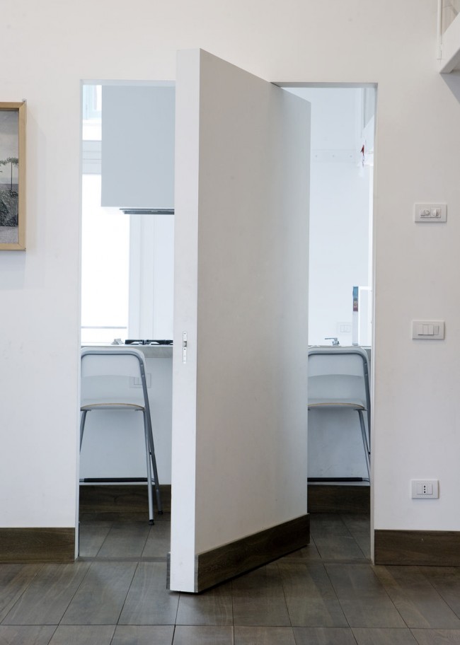 Porte intérieure secrète sans poignées dans un appartement minimaliste totalement blanc