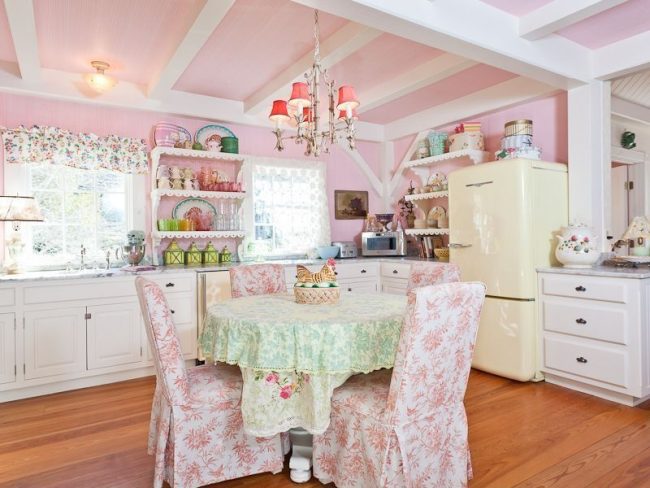 Cuisine shabby chic : décoration murale et plafond rose, lustre, housses de chaises colorées et set de cuisine beige