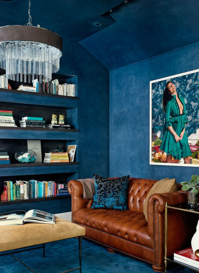 Bel intérieur de style fusion bleu avec un petit canapé Chesterfield marron