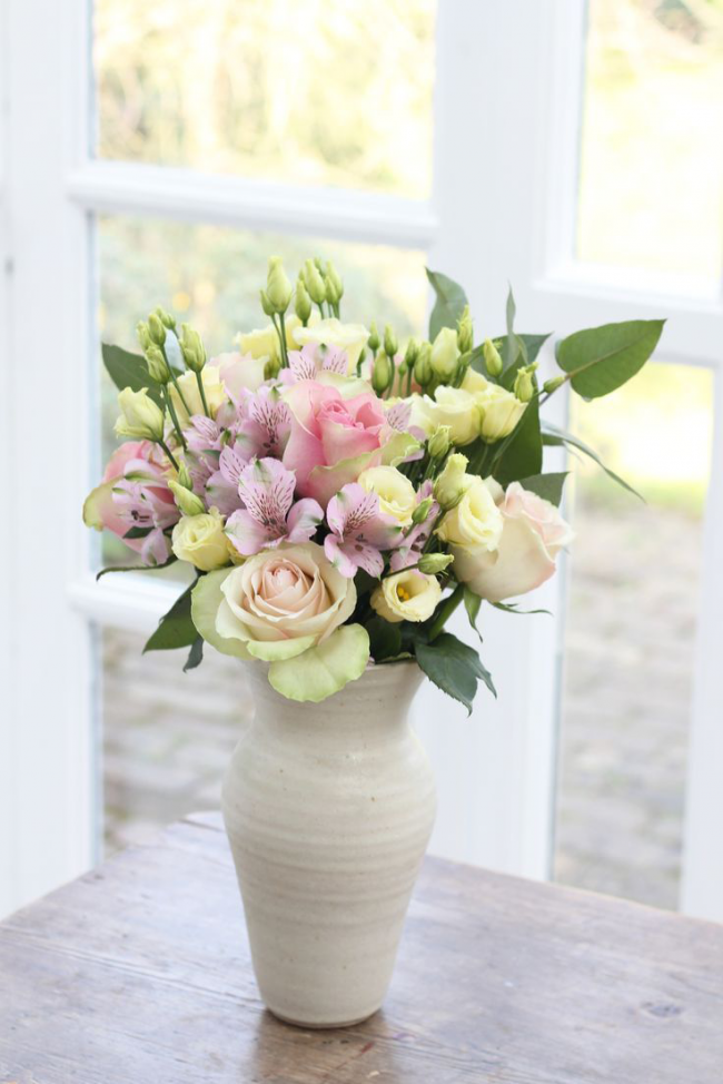 Roses dans un vase d'argile dans un coin lumineux de la pièce
