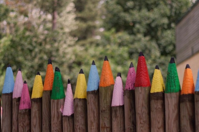 Clôtures en bois et clôtures pour la maison.  Une clôture en bois ou une clôture en rondins, taillée et peinte sous des crayons de couleurs, sera appréciée des amateurs d'humour en design