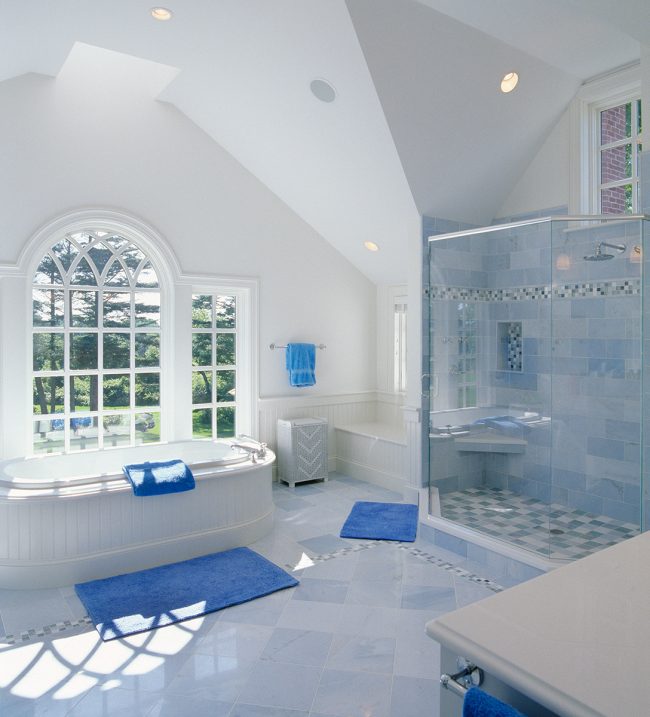 Salle de bain spacieuse dans une maison privée avec des luminaires blancs et des accents bleu vif sur les éléments décoratifs